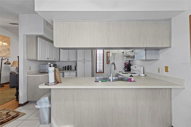 kitchen with sink, kitchen peninsula, a textured ceiling, white appliances, and light tile patterned floors