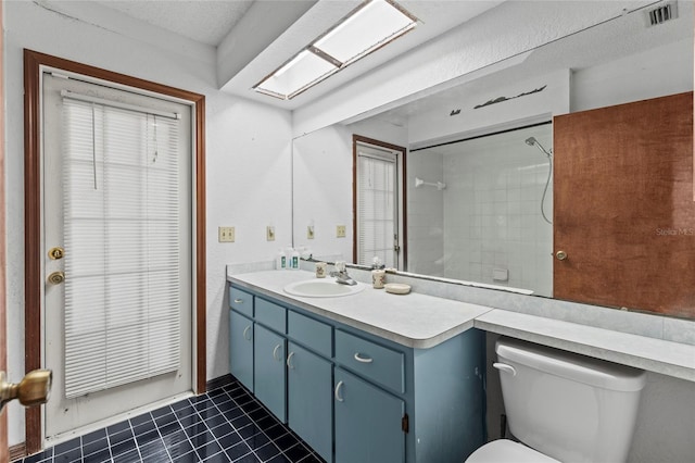 bathroom featuring tile patterned flooring, vanity, tiled shower, and toilet