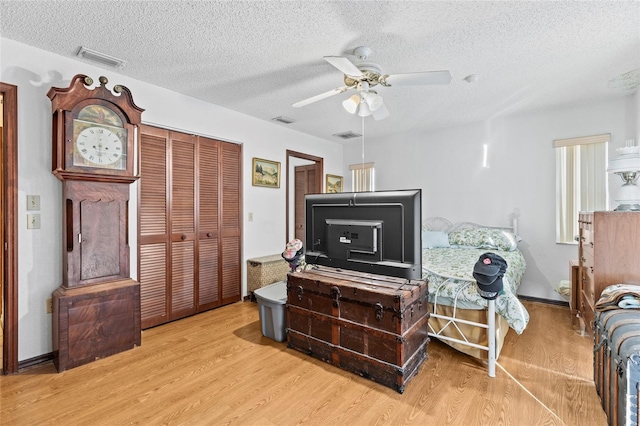 bedroom with a closet, ceiling fan, light hardwood / wood-style flooring, and a textured ceiling