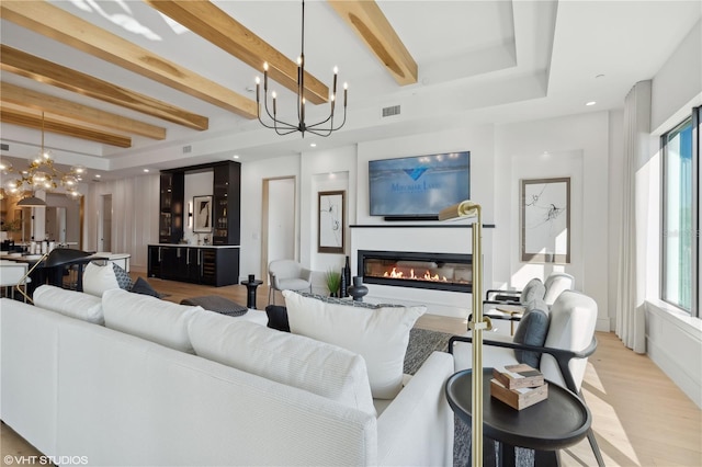 living room with beam ceiling, light hardwood / wood-style flooring, and a chandelier