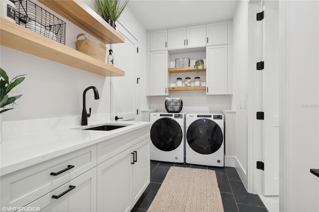 laundry room featuring cabinets, washing machine and dryer, dark tile patterned floors, and sink