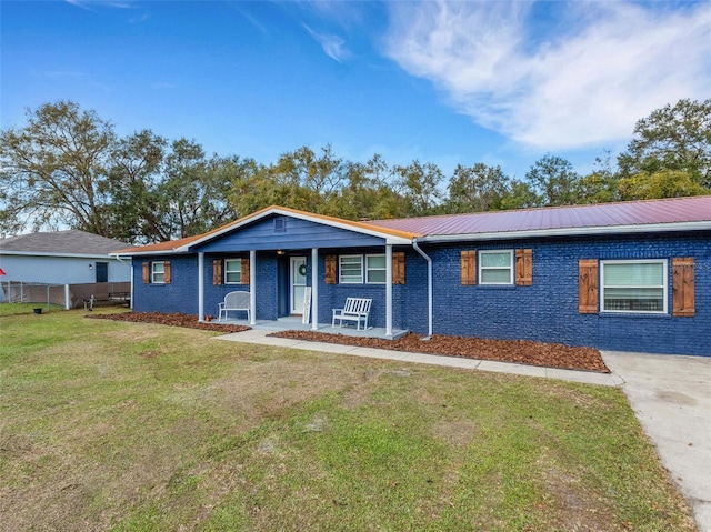 ranch-style house featuring a front yard, brick siding, metal roof, and fence