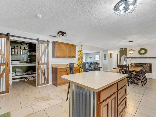 kitchen with a barn door, a kitchen island, and a textured ceiling