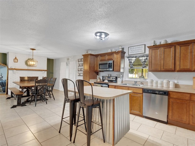 kitchen with hanging light fixtures, a kitchen breakfast bar, a textured ceiling, a kitchen island, and appliances with stainless steel finishes