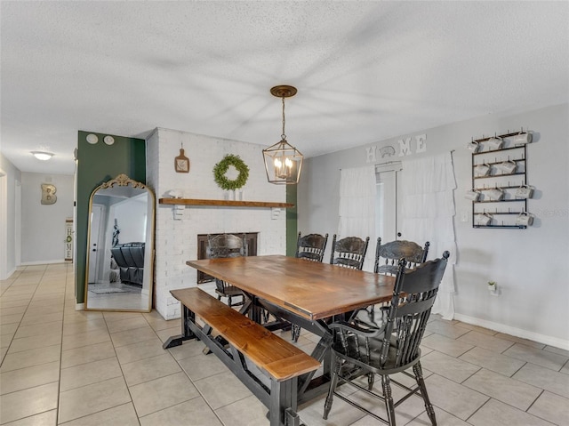 dining room with a fireplace, a textured ceiling, an inviting chandelier, and light tile patterned flooring