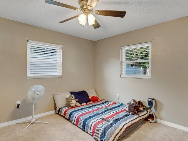 bedroom with ceiling fan, light colored carpet, and a textured ceiling