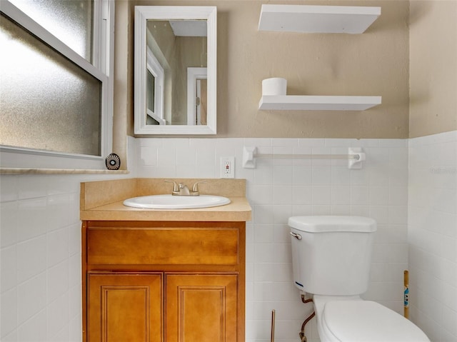 bathroom with vanity, tile walls, and toilet