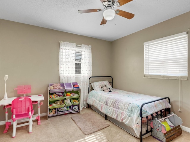 carpeted bedroom featuring ceiling fan, a textured ceiling, and multiple windows