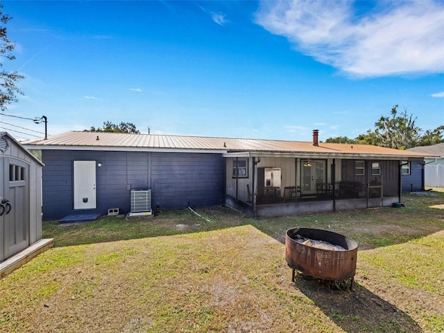 rear view of property with a lawn, a sunroom, metal roof, a shed, and an outdoor structure