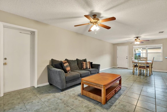 living room with ceiling fan, light tile patterned flooring, and a textured ceiling