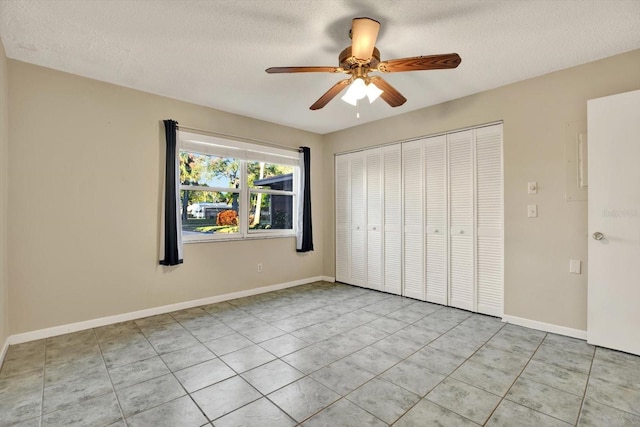 unfurnished bedroom featuring ceiling fan, a closet, light tile patterned flooring, and a textured ceiling