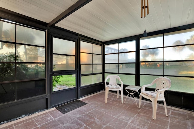 unfurnished sunroom with beamed ceiling, a water view, a healthy amount of sunlight, and wood ceiling