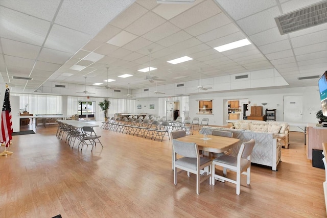 dining space featuring light hardwood / wood-style floors, a drop ceiling, and ceiling fan