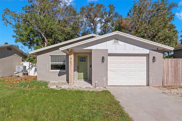 view of front facade with a front yard, fence, brick siding, an attached garage, and driveway