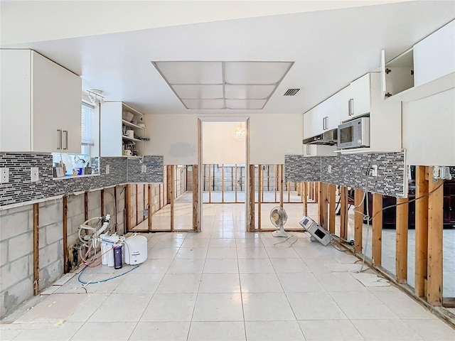 kitchen featuring white cabinets, light tile patterned floors, and tasteful backsplash