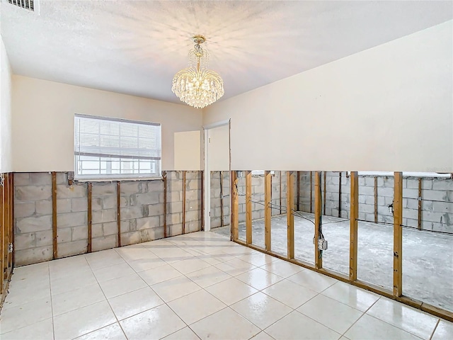 tiled empty room with a notable chandelier