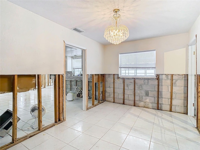 tiled empty room featuring a chandelier