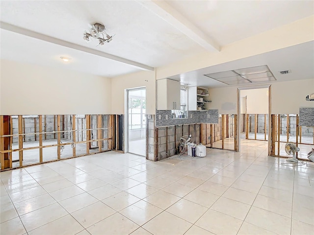 tiled empty room featuring beam ceiling