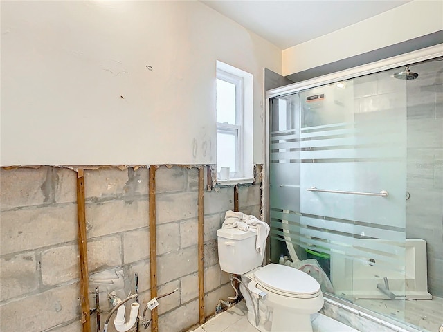 bathroom featuring a shower with door and toilet