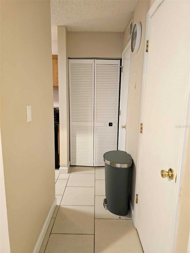 hall featuring a textured ceiling and light tile patterned flooring