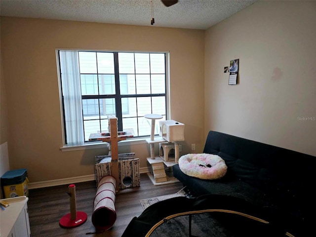 sitting room with a textured ceiling, ceiling fan, and dark wood-type flooring