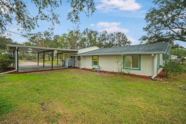 back of property with a carport and a lawn