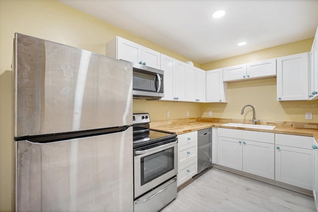 kitchen featuring white cabinets, sink, appliances with stainless steel finishes, and light hardwood / wood-style flooring