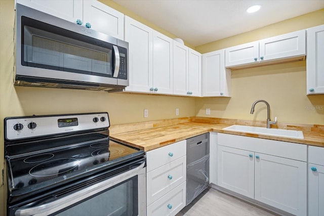 kitchen featuring wood counters, appliances with stainless steel finishes, white cabinets, and sink