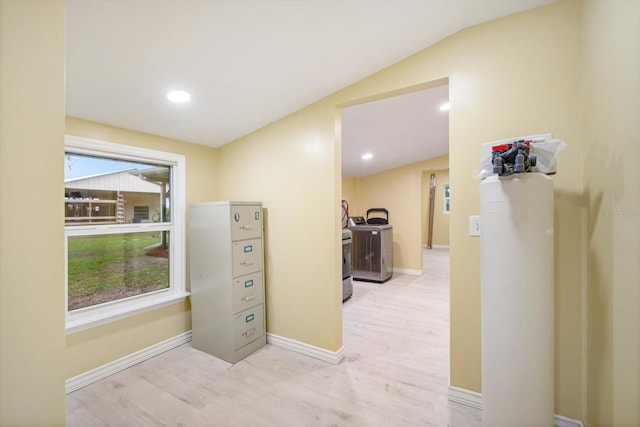 corridor featuring washer / clothes dryer, lofted ceiling, and light wood-type flooring