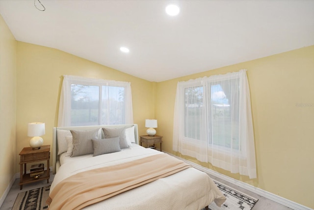 bedroom with vaulted ceiling and multiple windows