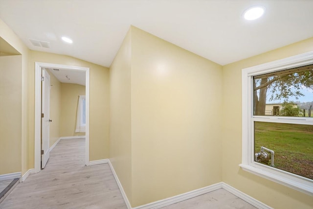 corridor with light hardwood / wood-style floors and vaulted ceiling