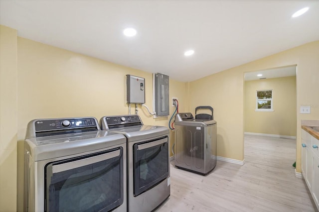 laundry area featuring electric panel, separate washer and dryer, and light hardwood / wood-style flooring