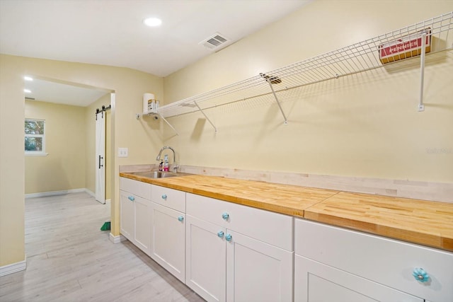 washroom with a barn door, light hardwood / wood-style flooring, and sink