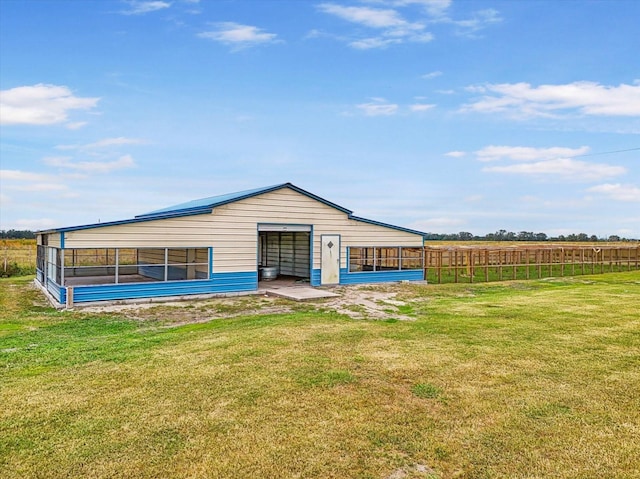 rear view of property with a lawn, an outbuilding, and a rural view