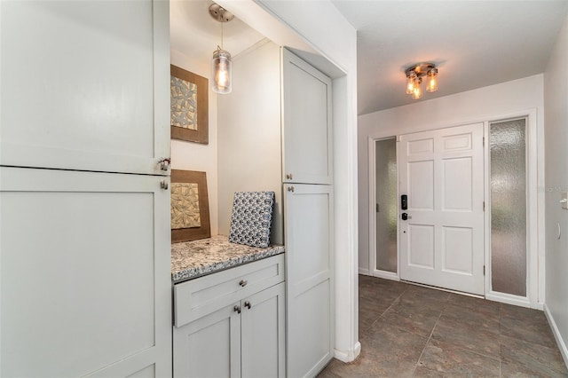 interior space featuring light stone counters, white cabinets, and hanging light fixtures