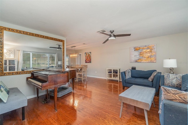 living room with ceiling fan with notable chandelier and hardwood / wood-style flooring