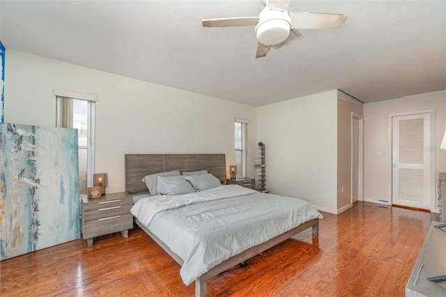 bedroom with multiple windows, wood-type flooring, a closet, and ceiling fan