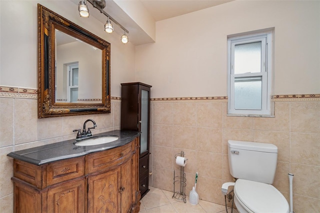 bathroom with tile patterned flooring, vanity, toilet, and tile walls