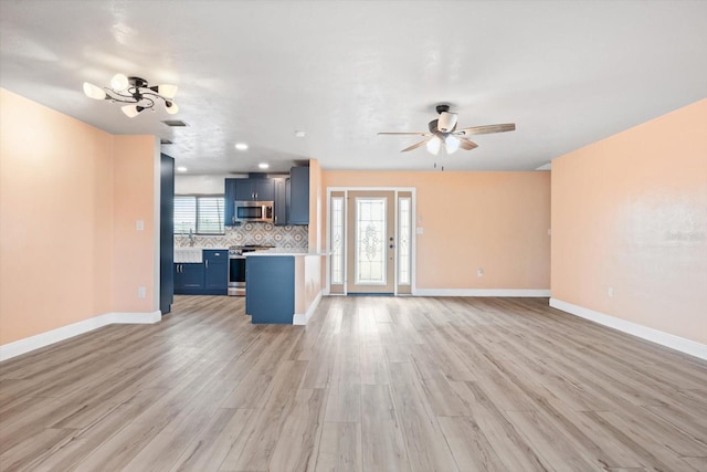 unfurnished living room featuring ceiling fan with notable chandelier, light hardwood / wood-style floors, and sink