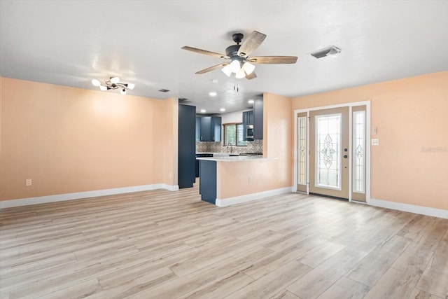 unfurnished living room with ceiling fan with notable chandelier, light hardwood / wood-style floors, and sink