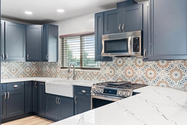 kitchen with light wood-type flooring, light stone countertops, appliances with stainless steel finishes, and tasteful backsplash