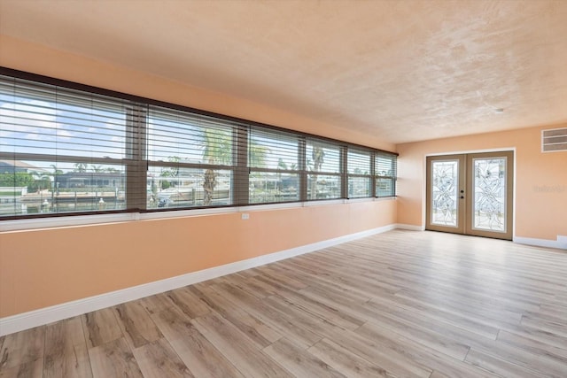 empty room with french doors and light hardwood / wood-style flooring