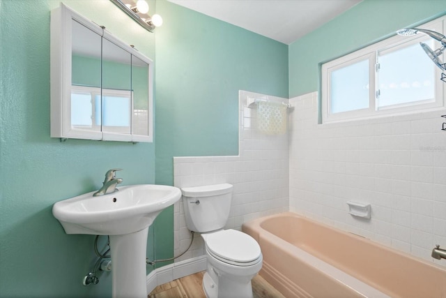 full bathroom featuring wood-type flooring, tiled shower / bath combo, toilet, and sink