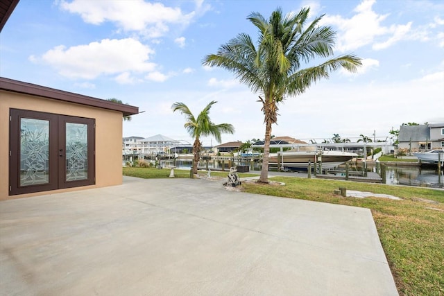 view of patio with a water view, a dock, and french doors