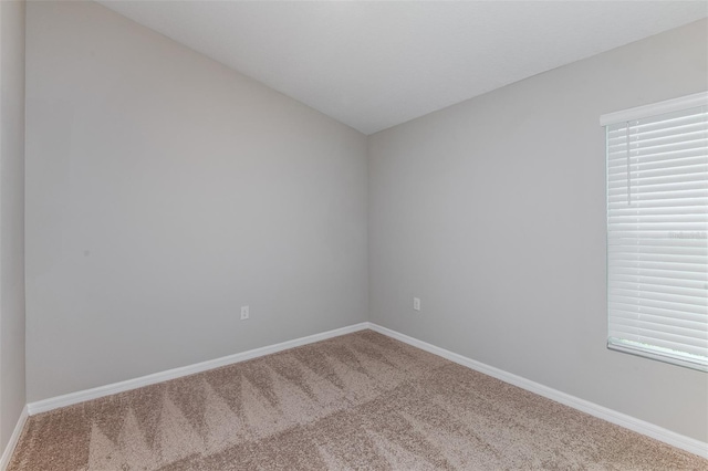 unfurnished room with lofted ceiling, carpet floors, and baseboards