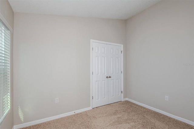 unfurnished bedroom with carpet, a closet, and baseboards