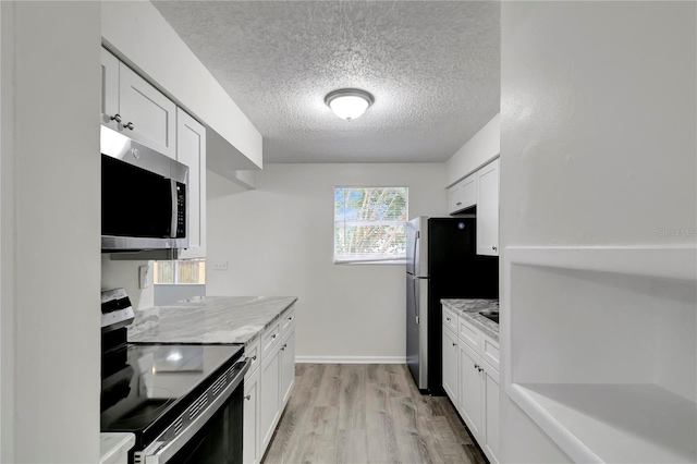 kitchen featuring light stone countertops, stainless steel appliances, light hardwood / wood-style flooring, a textured ceiling, and white cabinets