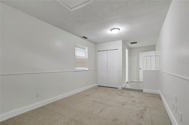 unfurnished bedroom featuring light colored carpet, a textured ceiling, and a closet