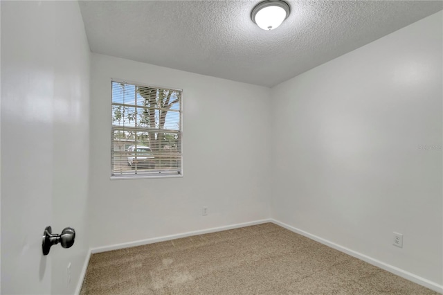 carpeted empty room featuring a textured ceiling