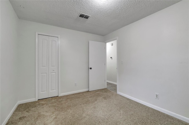 unfurnished bedroom with light carpet, a textured ceiling, and a closet